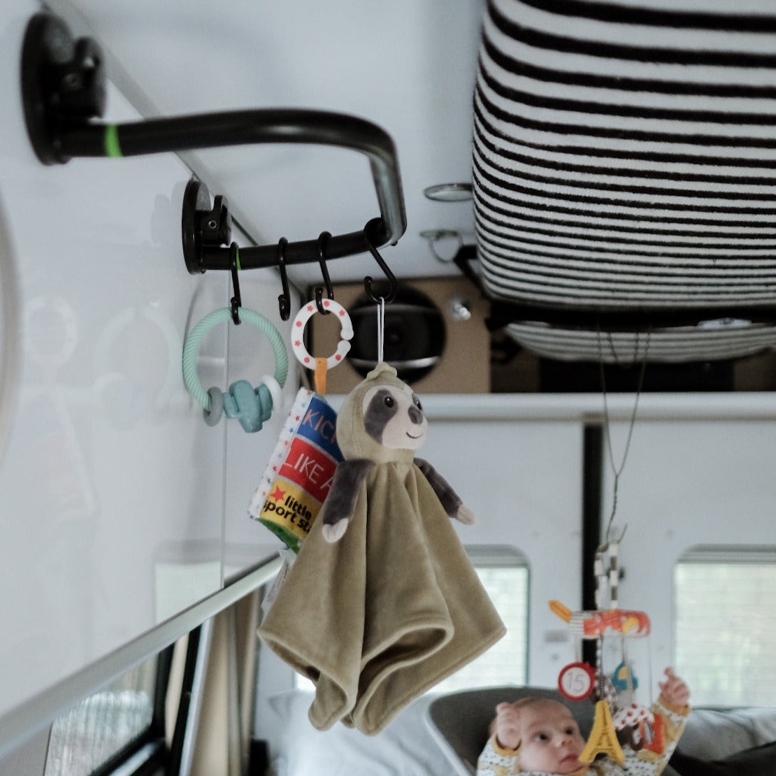 Doudou et jouets suspendus sur un Godry Hanger dans un camping car