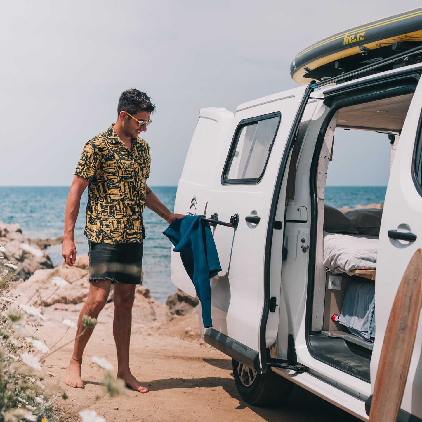 Surfeur fait sécher sa combinaison sur un séchoir Godry Hanger ventousé sur son van devant le spot