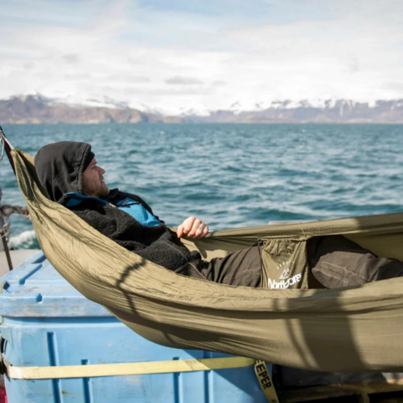 Voyageur observant la mer et les montagnes allongé dans son hamac sur le pont d'un bateau